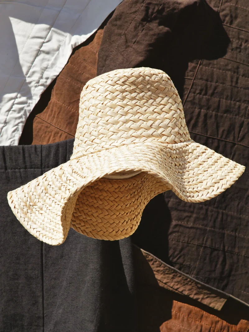 Studio illustrativo di un cappello da sole intrecciato dalla tesa asimmetrica.